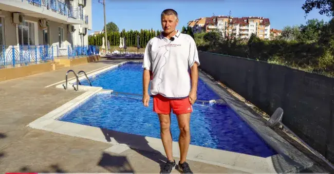 Чоловік на тлі басейну і комплексу